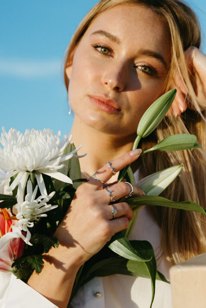 Manos femeninas con anillos de Urpi Shop y ramo de flores